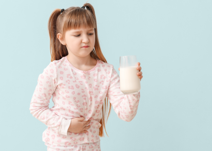 Kind dat met hand op de buik kijkt naar een glas melk.